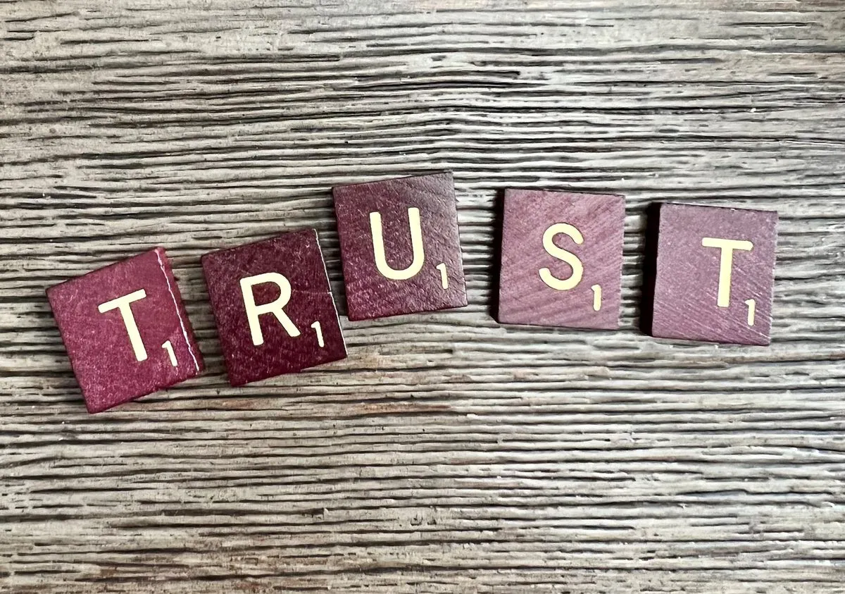 Wooden letter tiles spelling the word TRUST